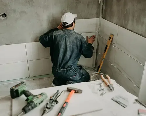 Tile setter installing wall tile in a bathroom remodel