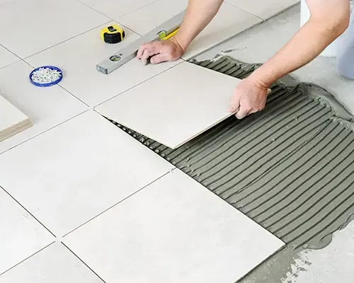 Installer setting a large-format floor tile into combed mortar